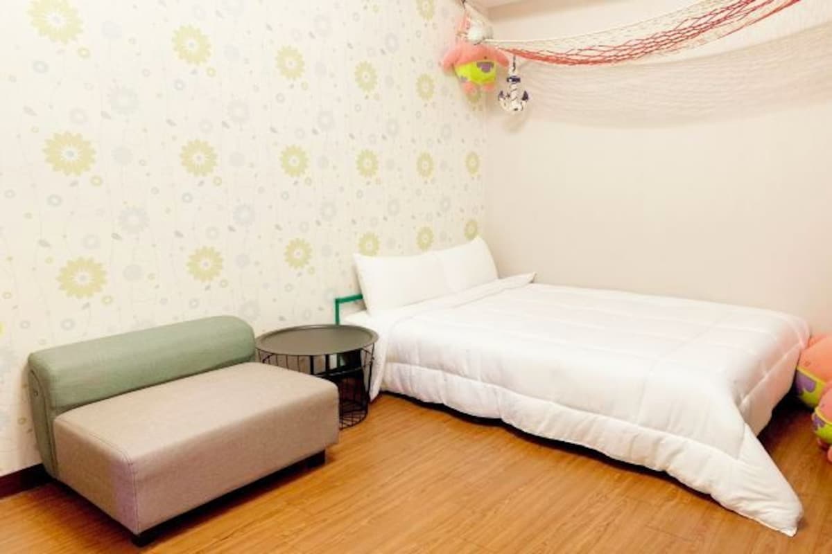 A bedroom with a bed, a sofa, a small round table, and a patterned wallpaper.