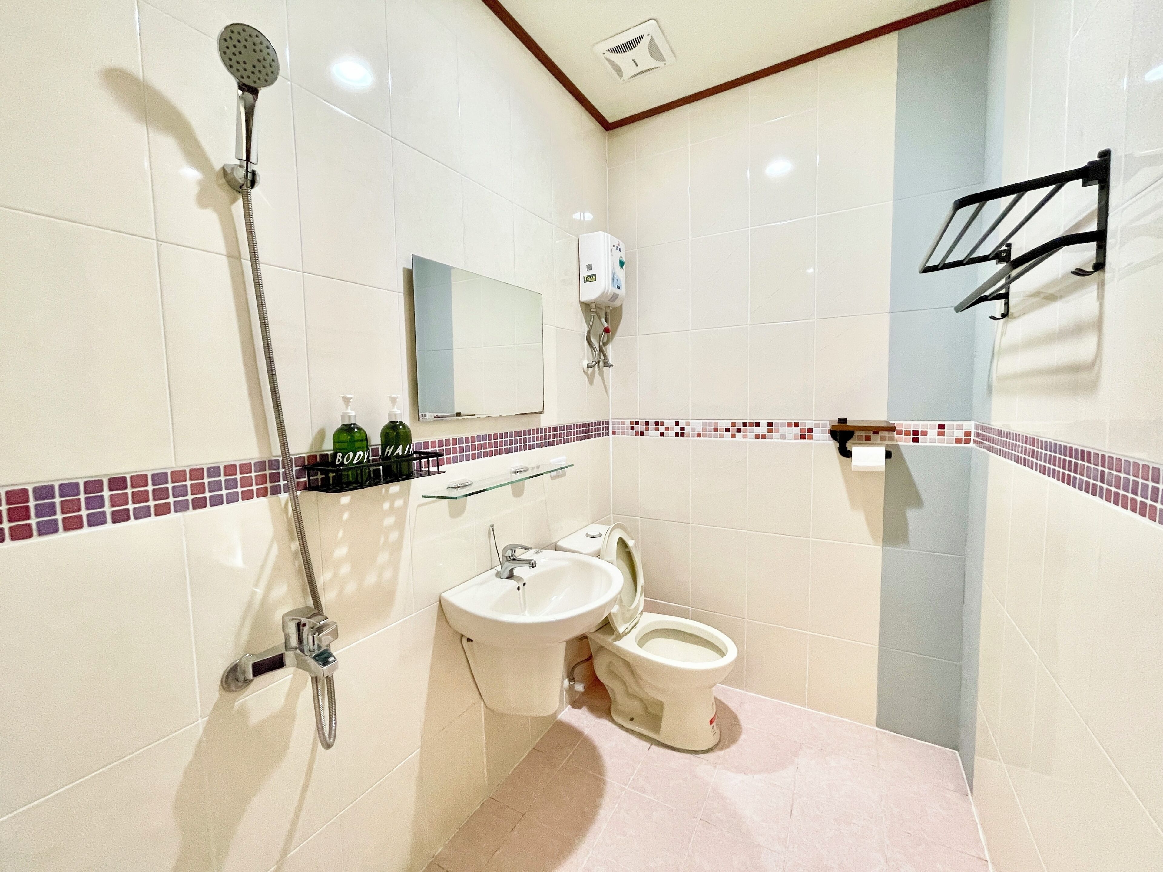 Un baño con ducha, lavamanos, inodoro y espejo.