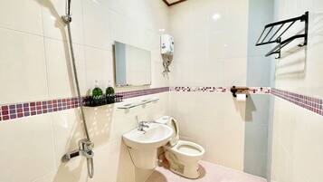 Un baño con ducha, lavamanos, inodoro y espejo.