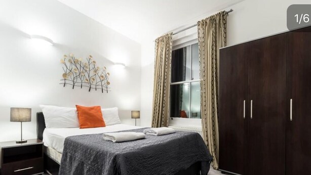Quarto com cama, mesas de cabeceira, guarda-roupa e uma obra de arte na parede.