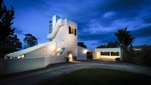 A modern house with a unique architectural design, featuring a prominent staircase and large windows. - National Award Winner with Stunning View (Havelock North)