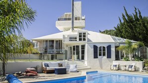 A modern house with a swimming pool, outdoor seating, and a large window overlooking the yard. - National Award Winner with Stunning View (Havelock North)