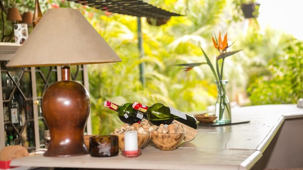 A table with a lamp, wine bottles, a candle, and a bowl of corks. - Hotel Rudi (Nairobi)