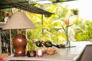 Une table avec une lampe, des bouteilles de vin, une bougie et un bol rempli de bouchons.