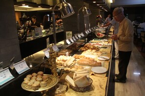 Un bufé con diversos alimentos y una persona de pie cerca del mostrador.