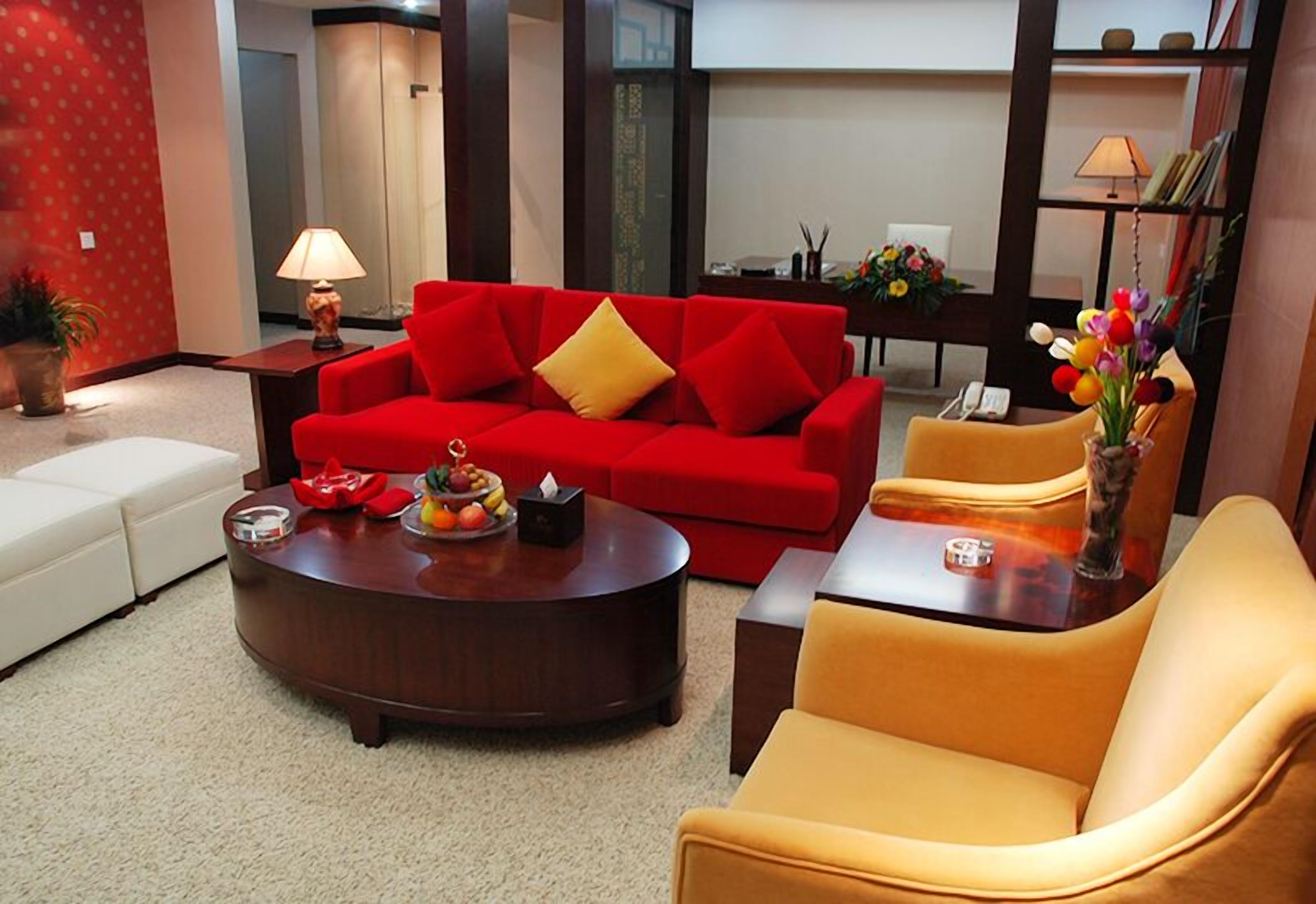 A living room with a red sofa, a yellow armchair, and a round coffee table.