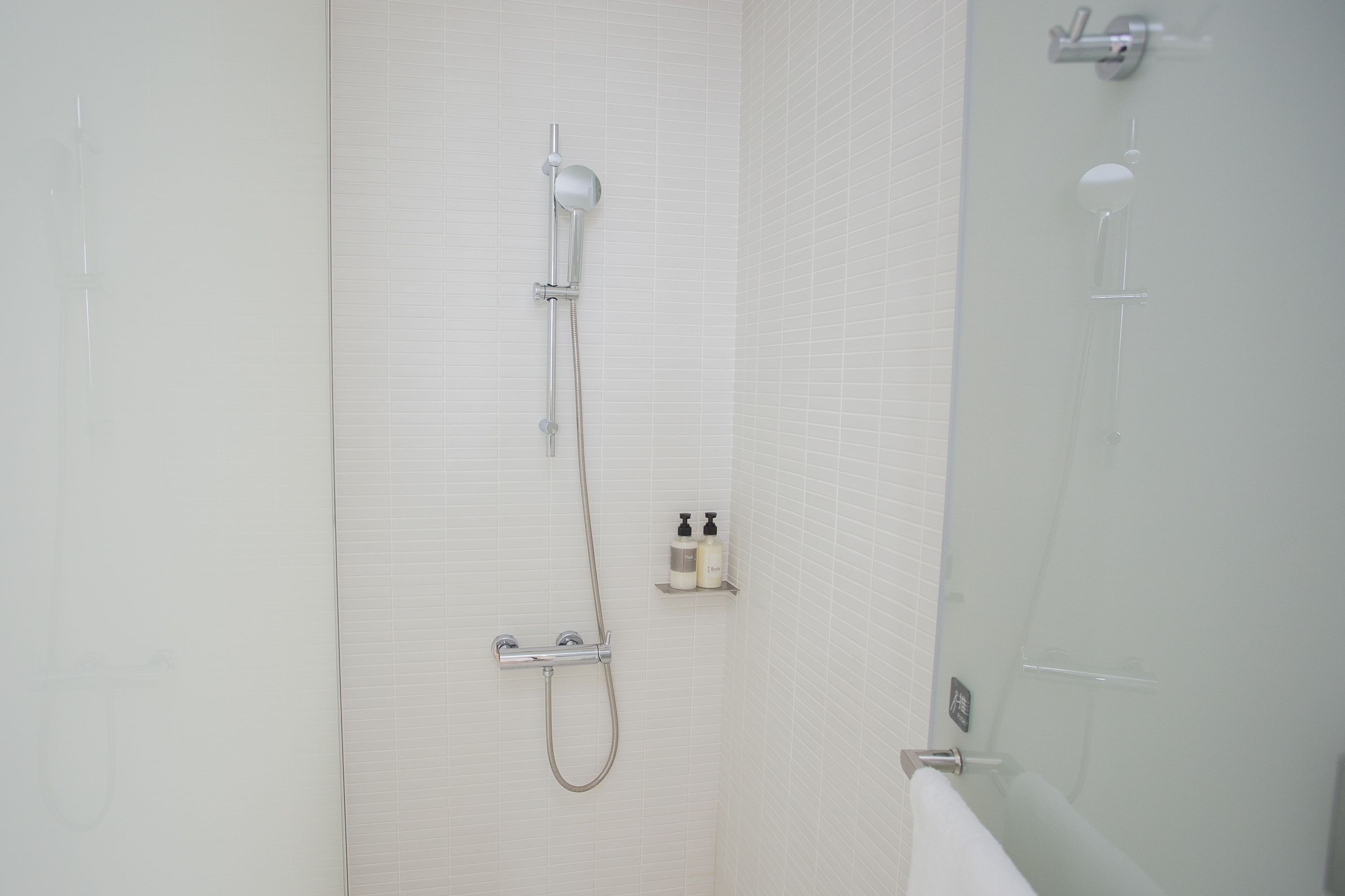 Une salle de bain dotée d’une douche à parois de verre, d’un pommeau de douche à main et d’un robinet mural.