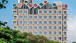 Un edificio moderno con una fachada de ventanas en cuadrícula y un diseño de tejado original con elementos sobresalientes.
