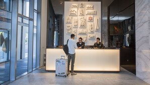 Un área de recepción moderna con un muro de vidrio, un mostrador de recepción y una pared decorada con obras de arte.