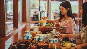 A dining table with food and drinks, a glass pitcher, and a tray with a salad.