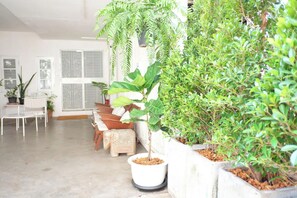 A spacious room with a concrete floor, a white chair, a small table, and a potted plant. - 12/14 HOME Studio (Bangkok)