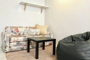 A living room with a floral sofa, a black coffee table, and a black bean bag. - 12/14 HOME Studio (Bangkok)