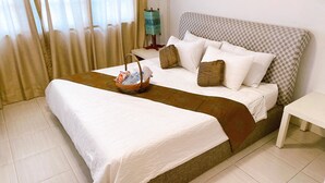 A neatly made bed with a checkered headboard, a bedside table, and a basket with items on the floor beside the bed. - 12/14 HOME Studio (Bangkok)
