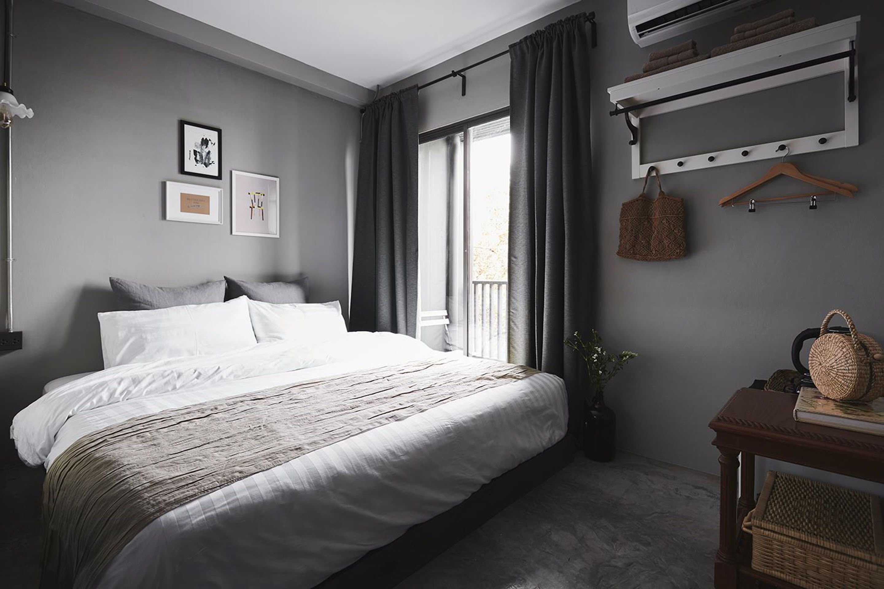 Camera da letto con un letto grande, un comodino, un cesto appeso e uno scaffale a parete con asciugamani.