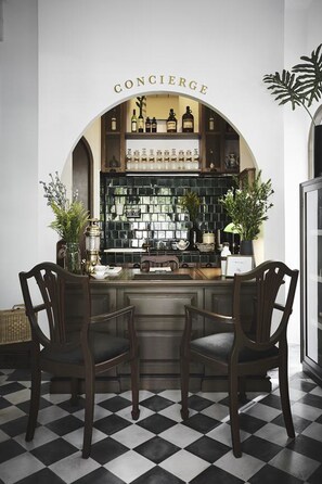 A bar area with a checkered floor, two wooden chairs, and a counter displaying bottles.