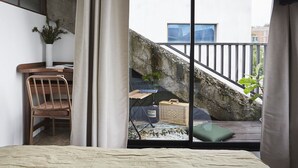 Une chambre comprenant un lit, un bureau, une chaise, une fenêtre et un balcon avec un escalier.