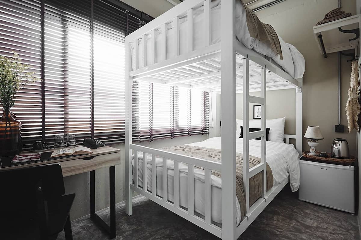 A bunk bed room with a desk, a lamp, and a small refrigerator.