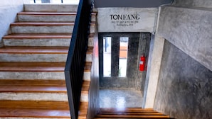 Una escalera con escalones de madera que conduce a una puerta con la etiqueta "TONFANG" e información de contacto.