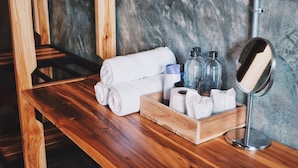 Banco de madera con toallas, artículos de aseo y un espejo en un ambiente tipo spa.