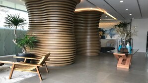 Un vestíbulo moderno con una estructura cilíndrica única, una zona de estar con una silla de mimbre y una mesa de cristal con adornos.