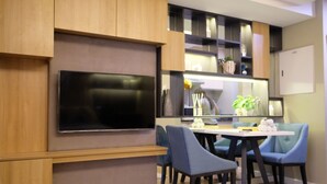 Una cocina moderna con televisor integrado, sillas azules y muebles de madera.