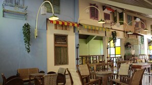 A spacious indoor area with multiple wooden tables and chairs, a hanging plant, and a variety of hanging lights. - Omah Njonja Bed & Brasserie (Depok)