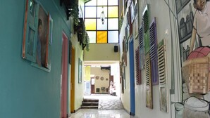 A hallway with colorful walls, a tiled floor, and a staircase leading to another area. - Omah Njonja Bed & Brasserie (Depok)