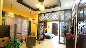 A room with a wooden floor, a bed with a blue bedspread, a chair, a table, and a potted plant. - Tuti Lakeside Homestay (Hanoi)
