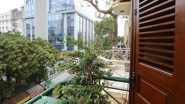 A view from a balcony overlooking a modern building with large windows and a green railing. - Tuti Lakeside Homestay (Hanoi)