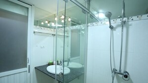 A modern bathroom with a glass shower enclosure, two sinks, and a vanity with a mirror. - Tuti Lakeside Homestay (Hanoi)
