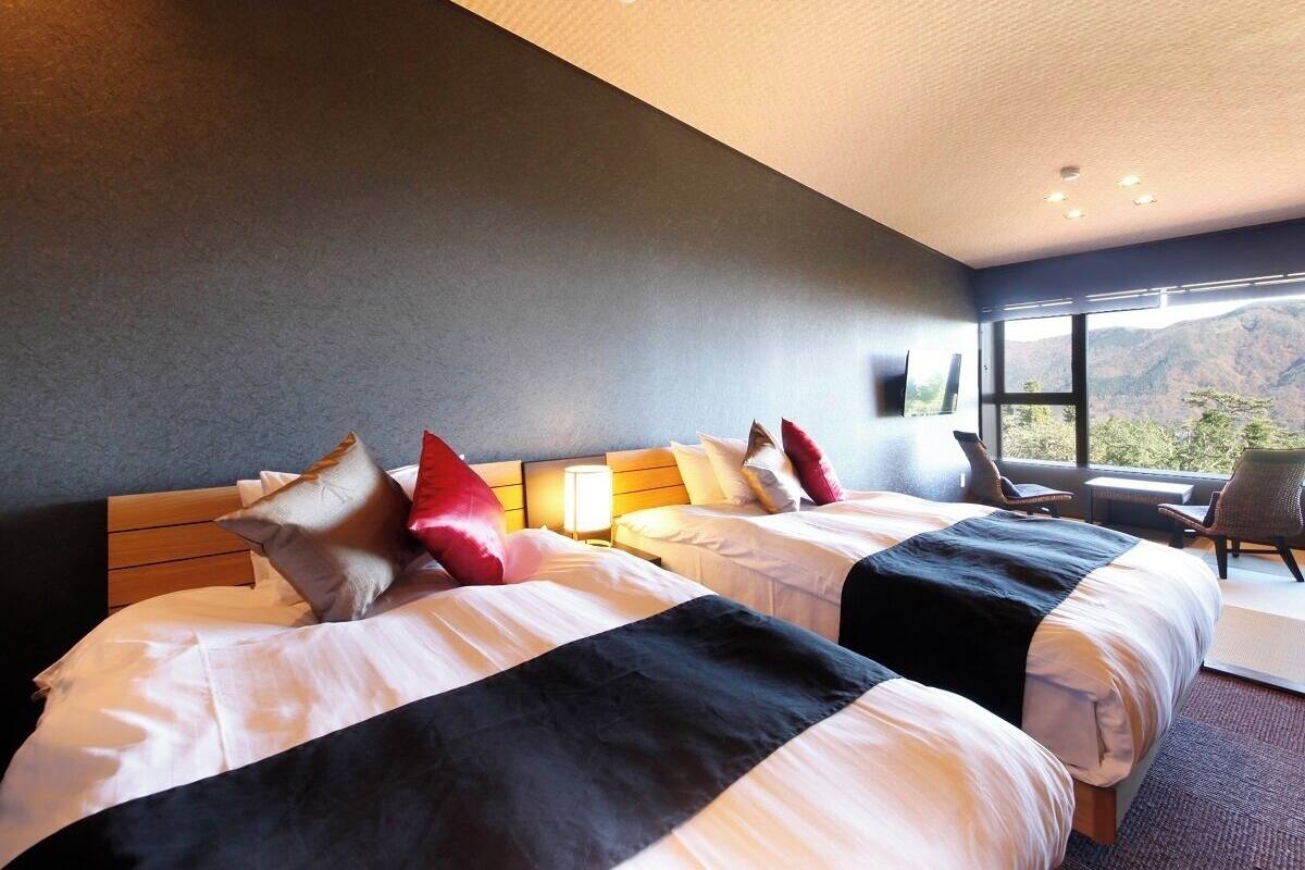 Quarto de hotel com duas camas, uma janela grande e vista para o exterior.