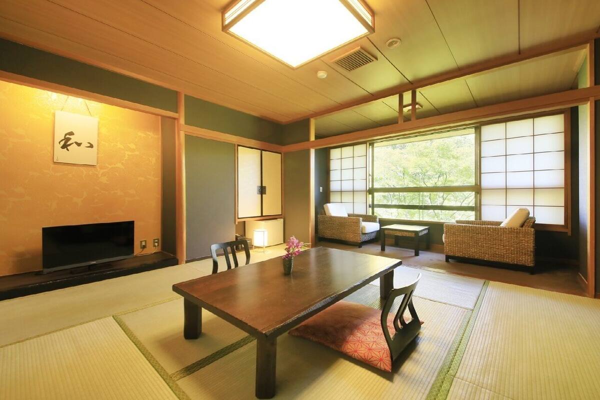 Um quarto japonês tradicional com tatames, uma mesa baixa, um sofá e portas deslizantes.