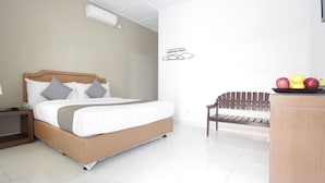 Una habitación de hotel moderna con cama, mesita de noche, banco y frutero.