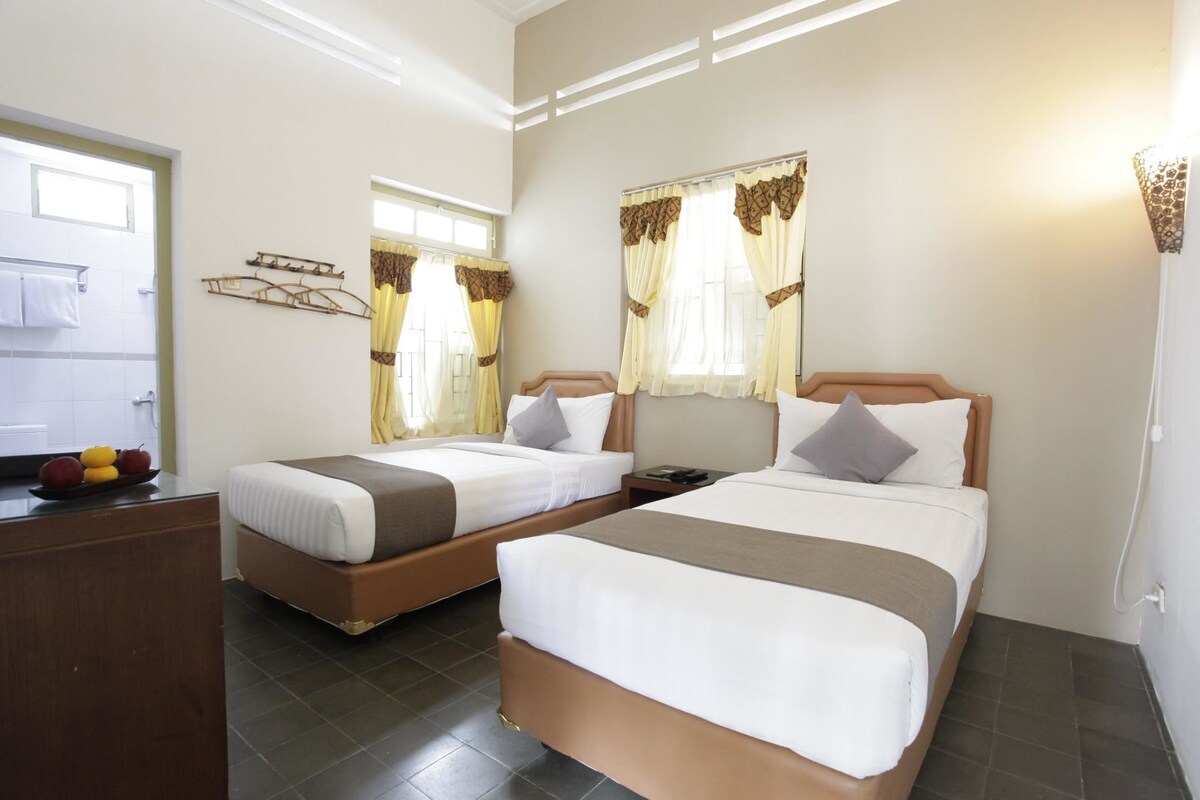 Habitación de hotel con dos camas, un escritorio y un frutero.