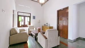 Una sala de estar con dos sofás, una mesa de centro, un aparador y una puerta de madera.