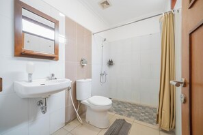 Une salle de bain équipée d’un lavabo, de toilettes, d’une douche et d’un miroir.