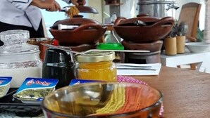 Un chef preparando comida en una cocina con varios utensilios y productos visibles.