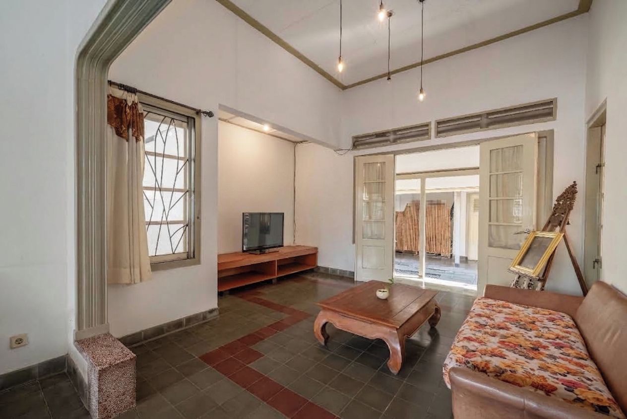 A living room with a television, a coffee table, a sofa, and a painting on the wall.