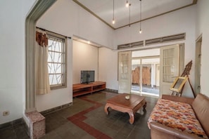 Una sala de estar con televisión, una mesa de centro, un sofá y un cuadro en la pared.