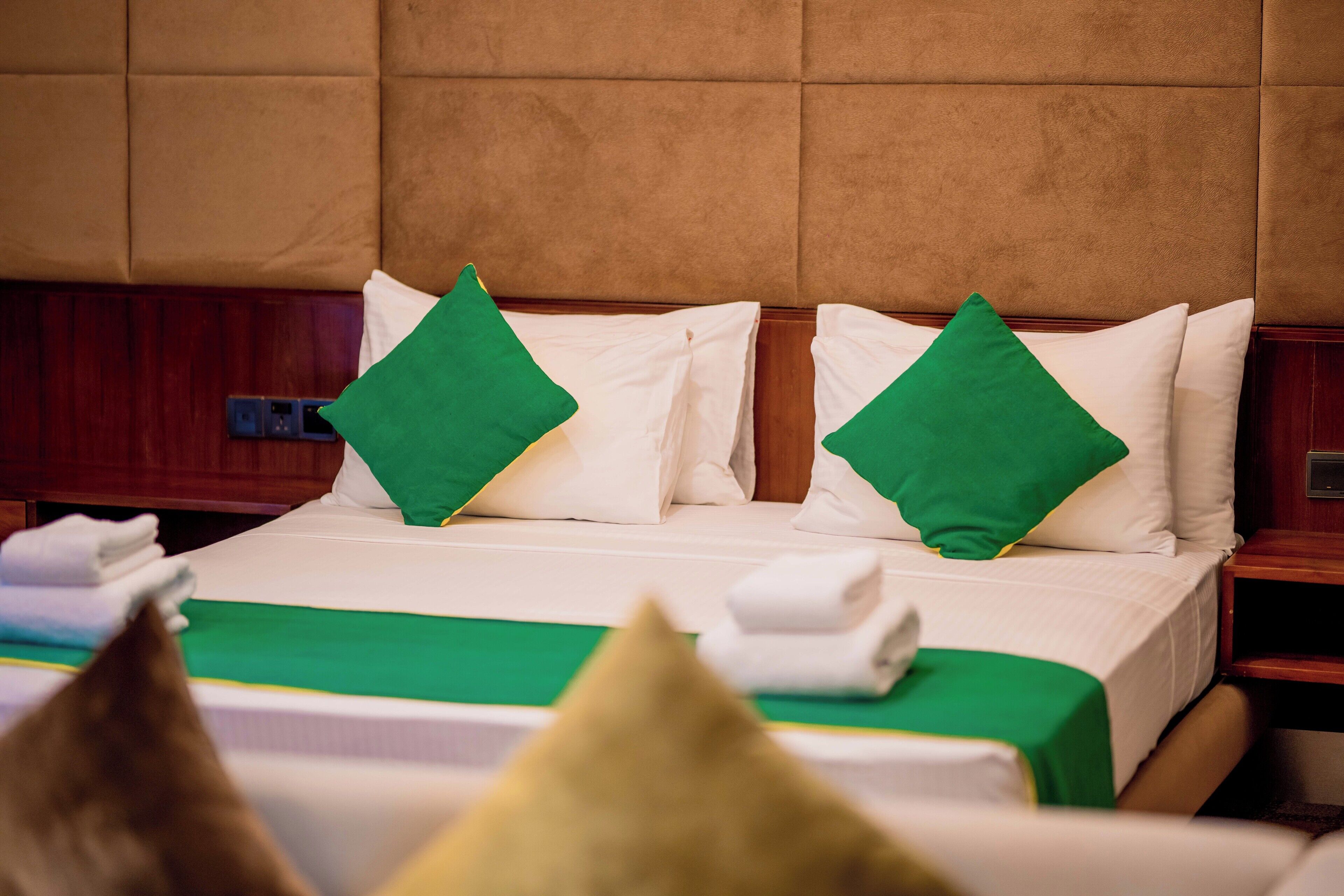 A hotel room with a bed, pillows, and a nightstand.