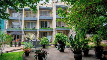 A multi-story building with balconies, potted plants, and outdoor seating.