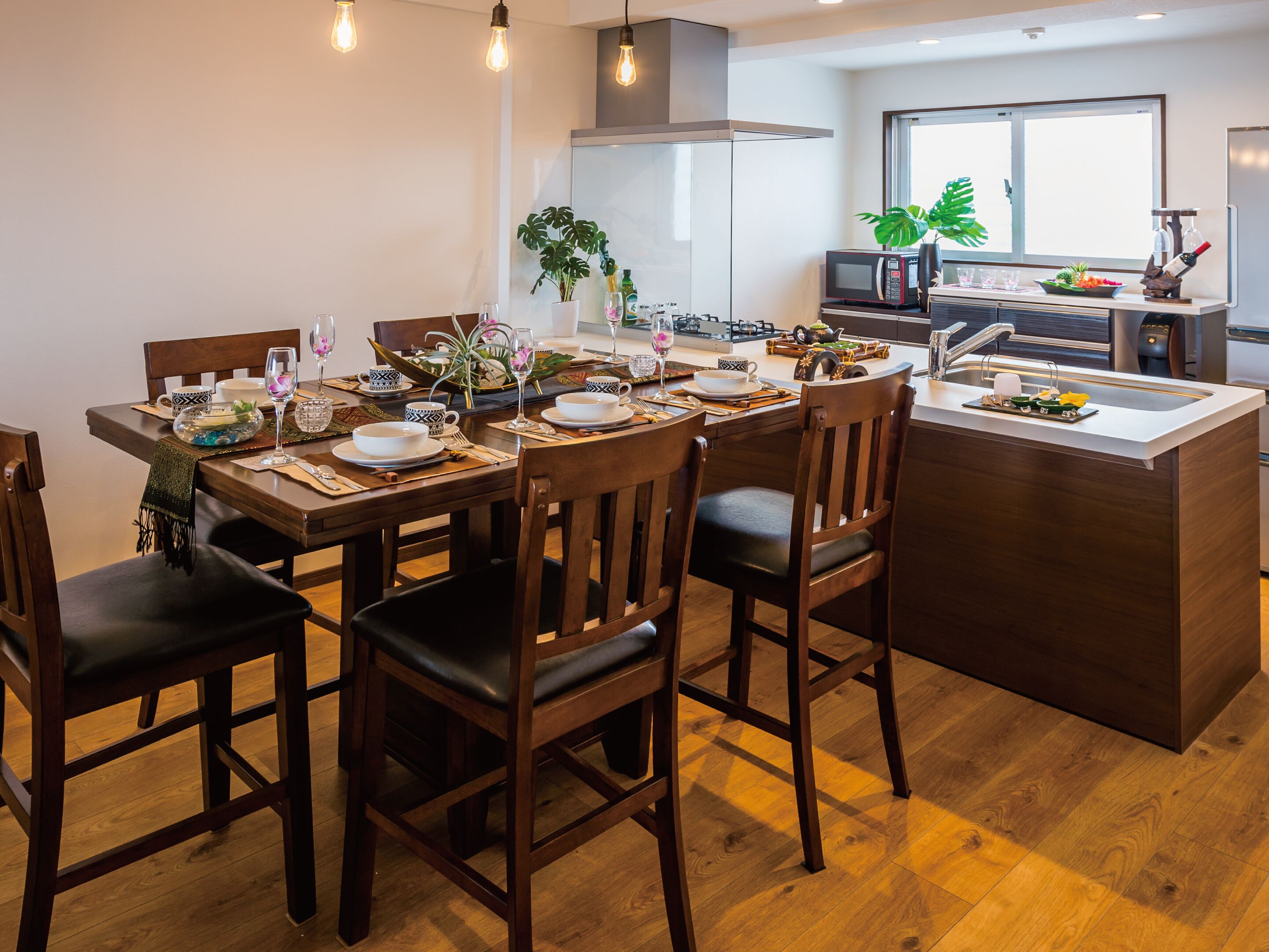 A modern kitchen with a central island, wooden chairs, and a dining table set for four.