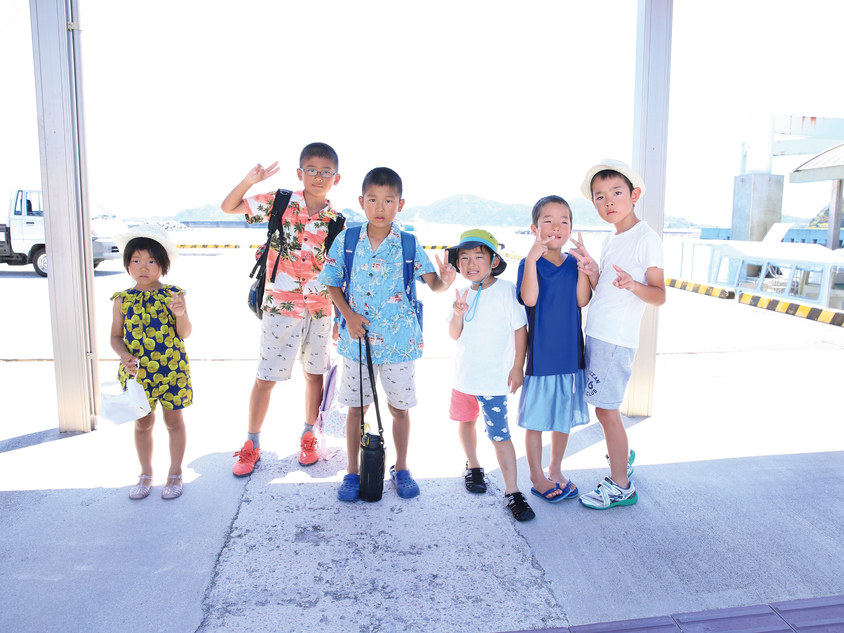 A group of people standing in an outdoor area with a concrete floor and metal railings.