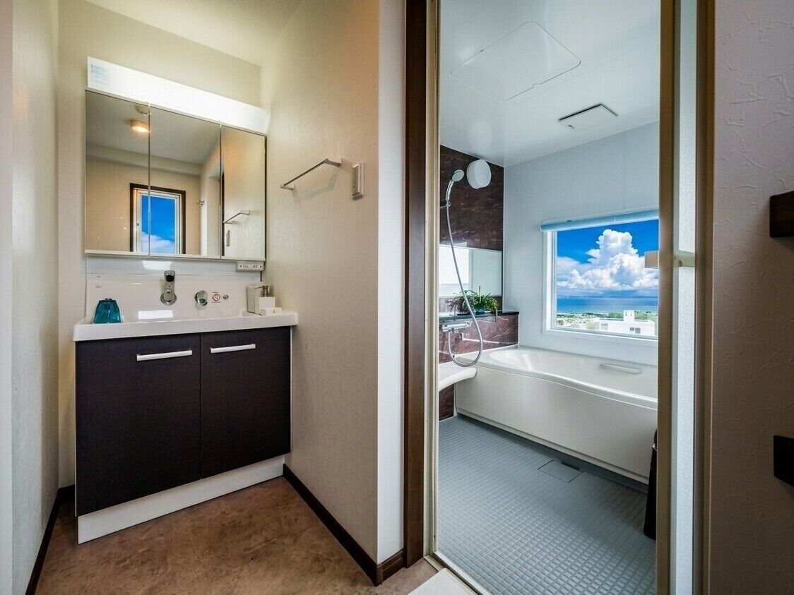 A modern bathroom with a large mirror, a sink, and a shower.