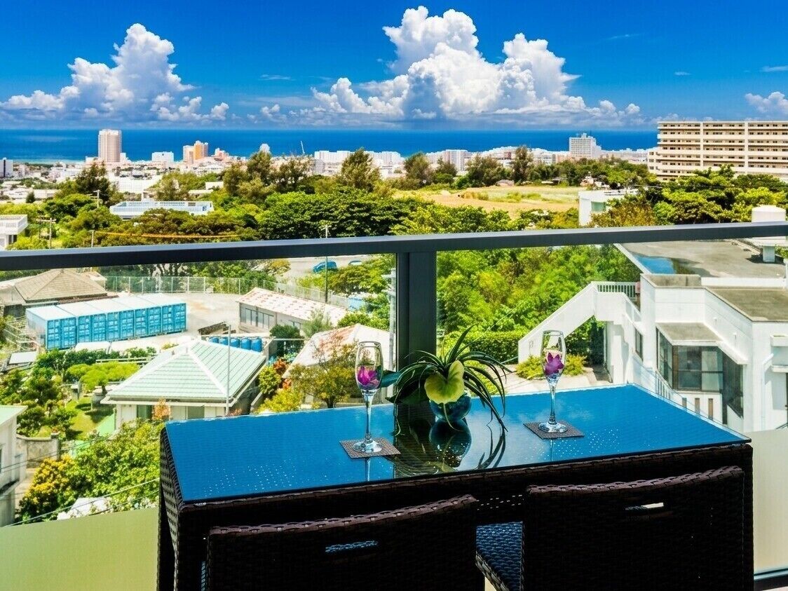 A balcony with a table, two glasses, and a plant.