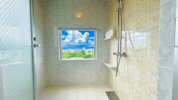 A shower with a window, tiled walls, and a view of greenery.