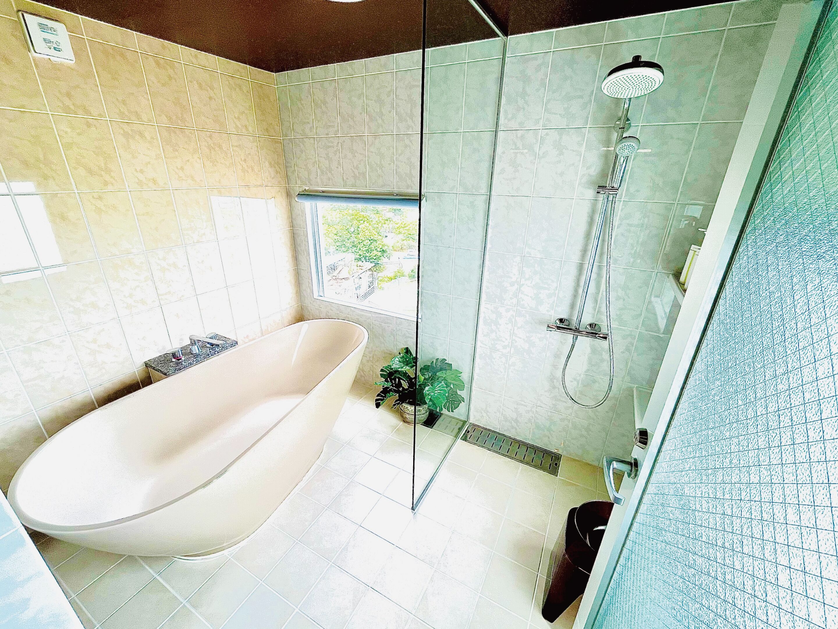 Un baño moderno con una bañera independiente, ducha con mampara de vidrio y ventana con vistas al exterior.