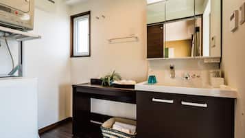 A modern bathroom with a white sink, dark cabinets, a mirror, and a small window.
