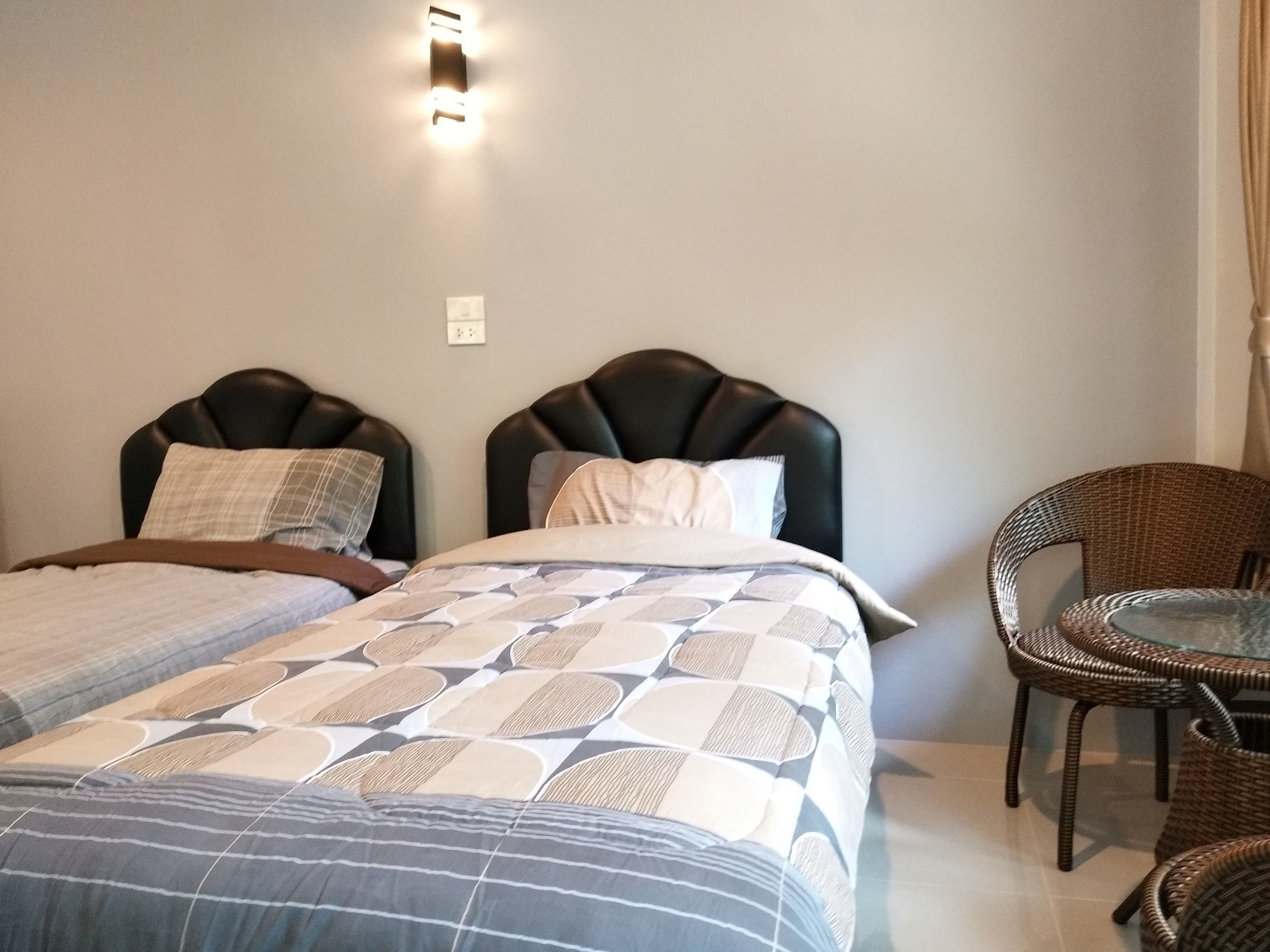 A bedroom with two beds, a chair, and a table.