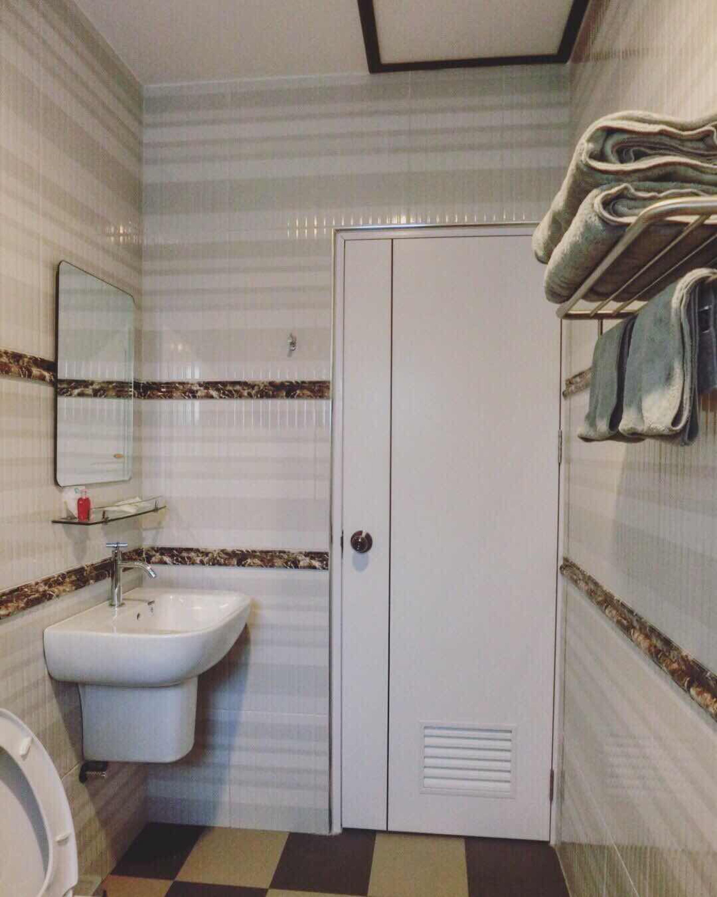 Une salle de bain équipée d’un lavabo, d’un miroir, de toilettes et d’une armoire.